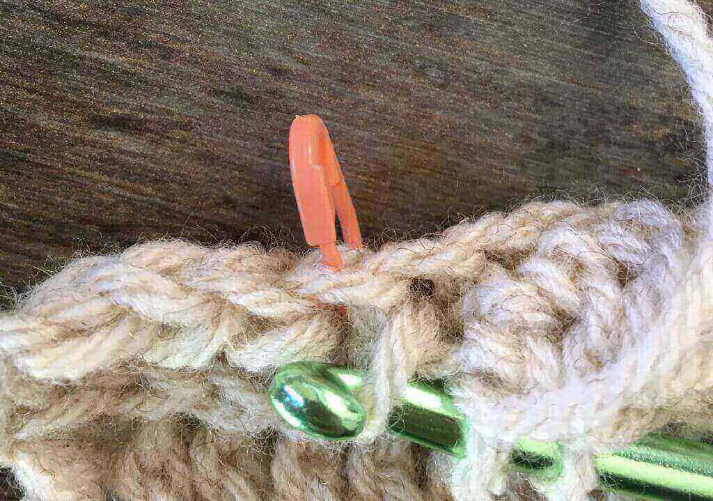 A crochet hook inserted into the third loop of a half double crochet stitch.