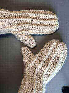 A pair of chunky white crochet mittens made with wool blend yarn.